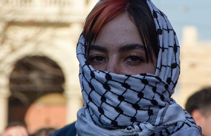 Un'attivista con la faccia coperta dalla kefiah a una manifestazione a sostegno della causa palestinese